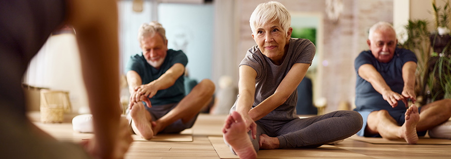 Three older adults stretch during a yoga class.