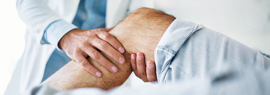 A doctor examines a senior patient’s knee.