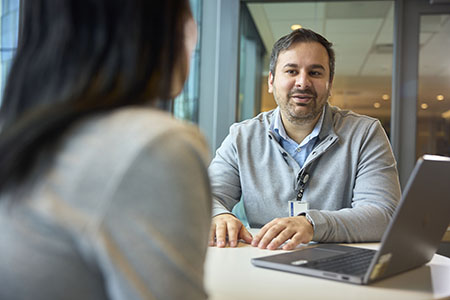 A doctor sits at a table and chats with another person.