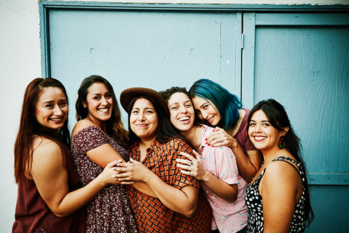 A group of 6 women laughing and hugging