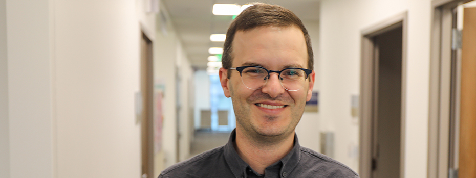 A man smiles as he stands in a hallway.
