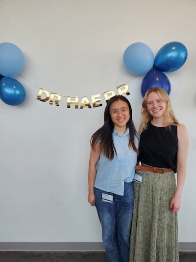 Two women standing with balloons.