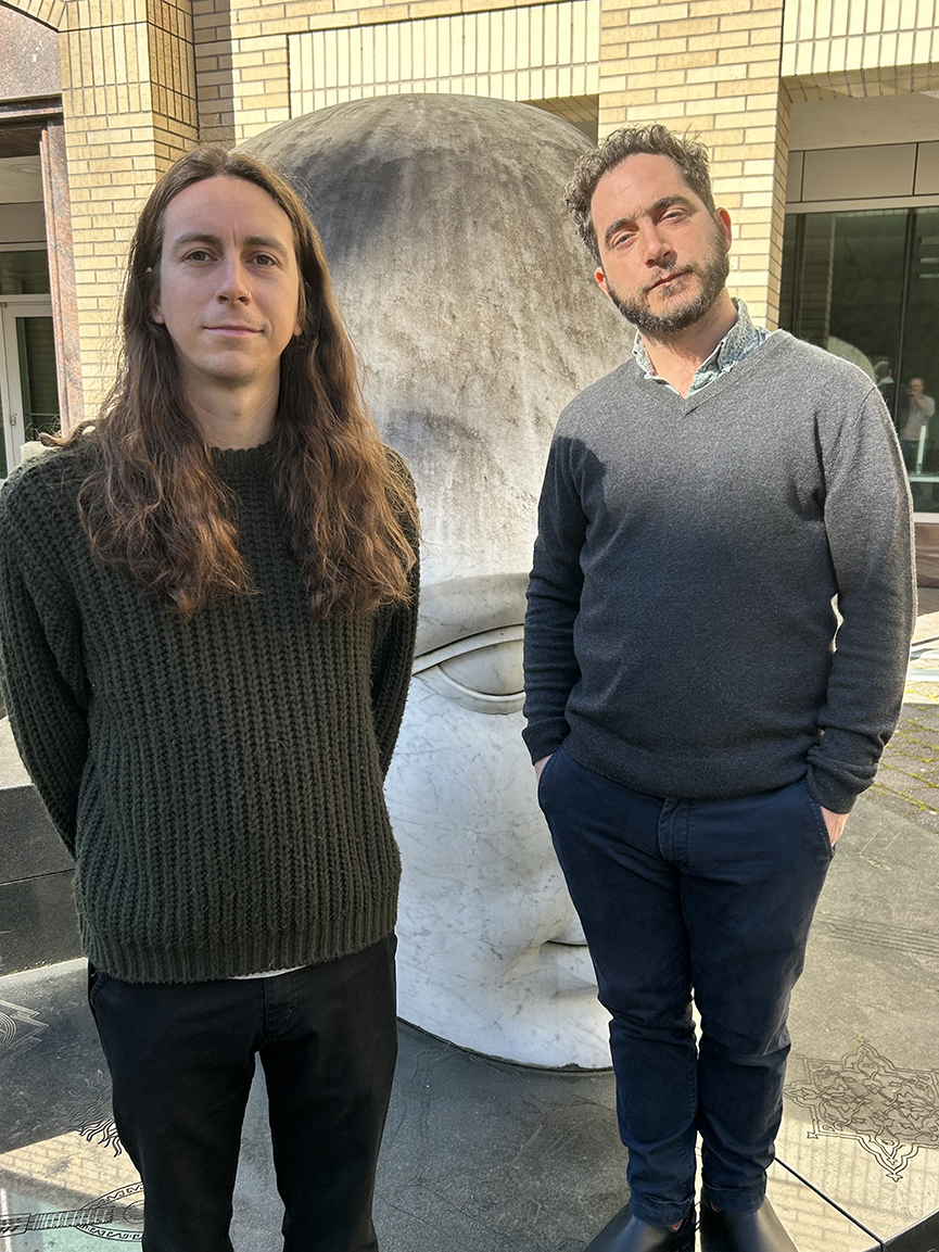 Austin Schubert & Dr Arpy Saunders stand in front of large sculpture in OHSU research campus courtyard