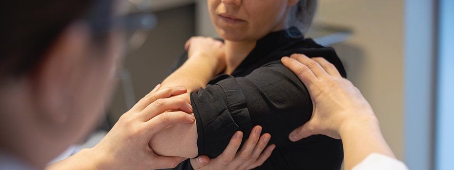 A healthcare provider examines a patient’s upper arm, which is in a compression wrap.