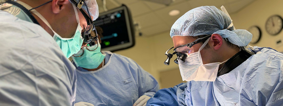Three people in surgical scrubs perform surgery in a hospital operating room at Oregon Health & Science University.