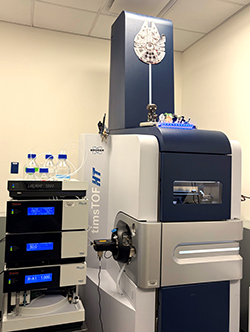 Bruker timsTOF HT mass spectrometer with attached liquid chromatography modules and solvent bottles.