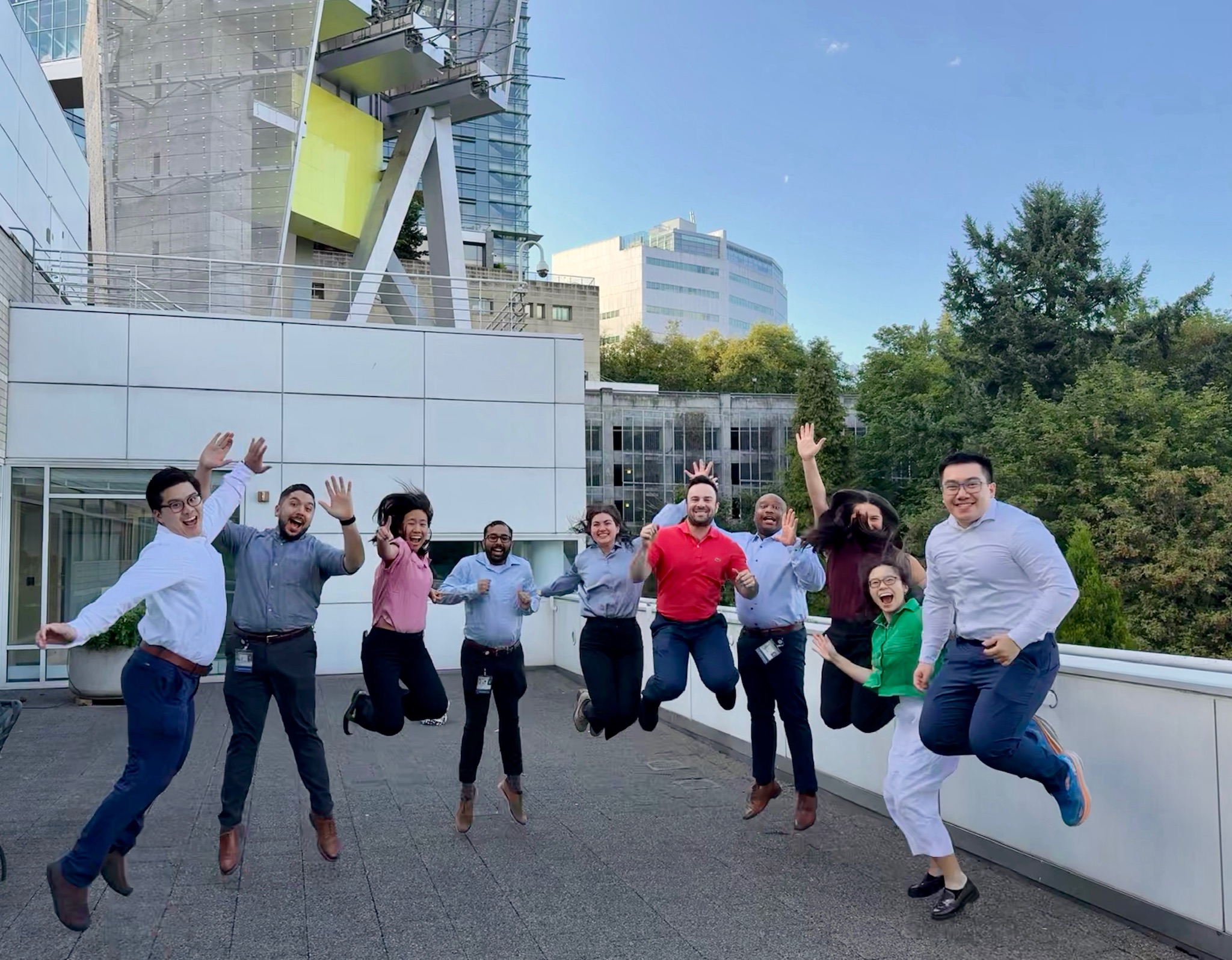 A group of ten people stand on a balcony jumping in the air together.