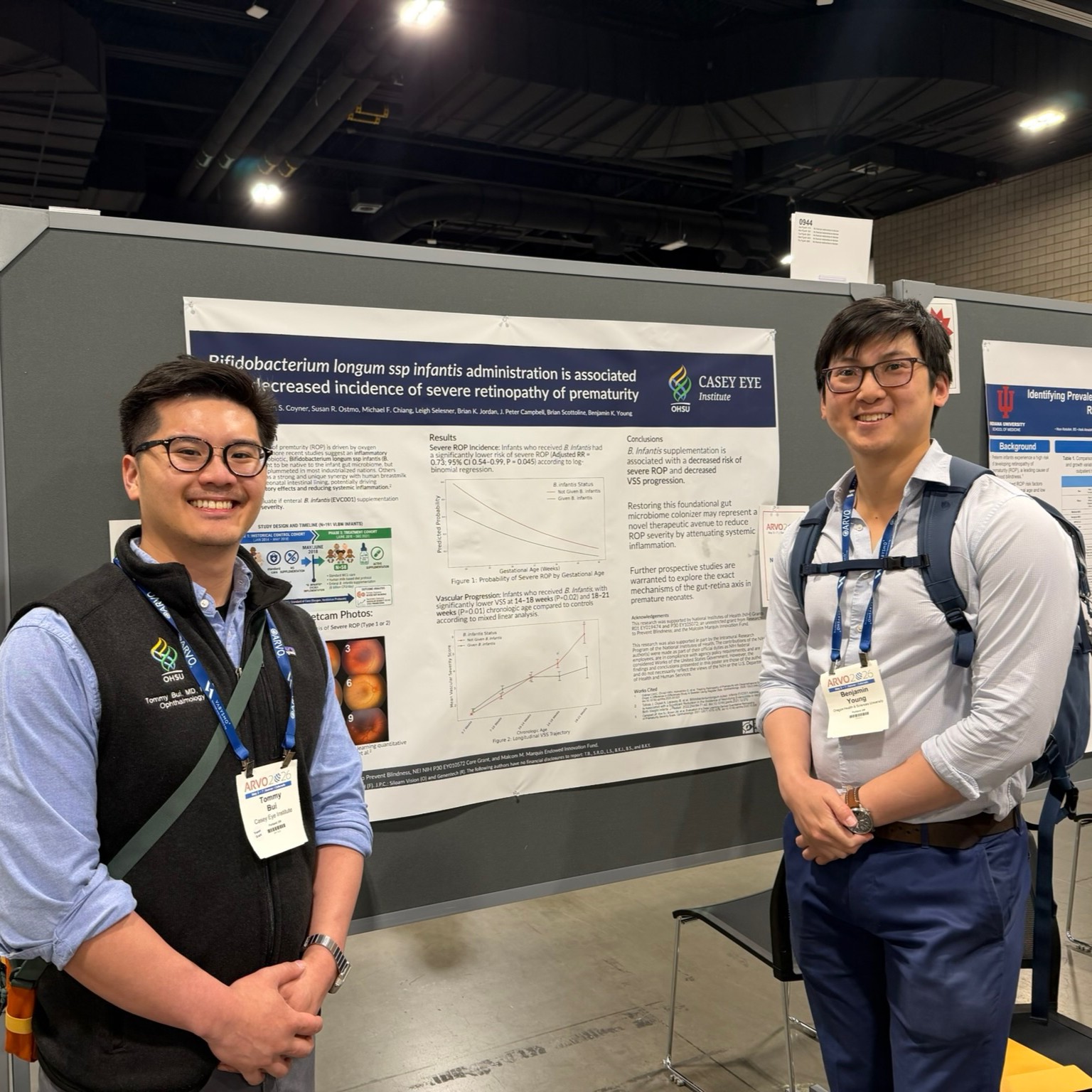 Two men stand in front of a scientific research poster smiling at the camera.