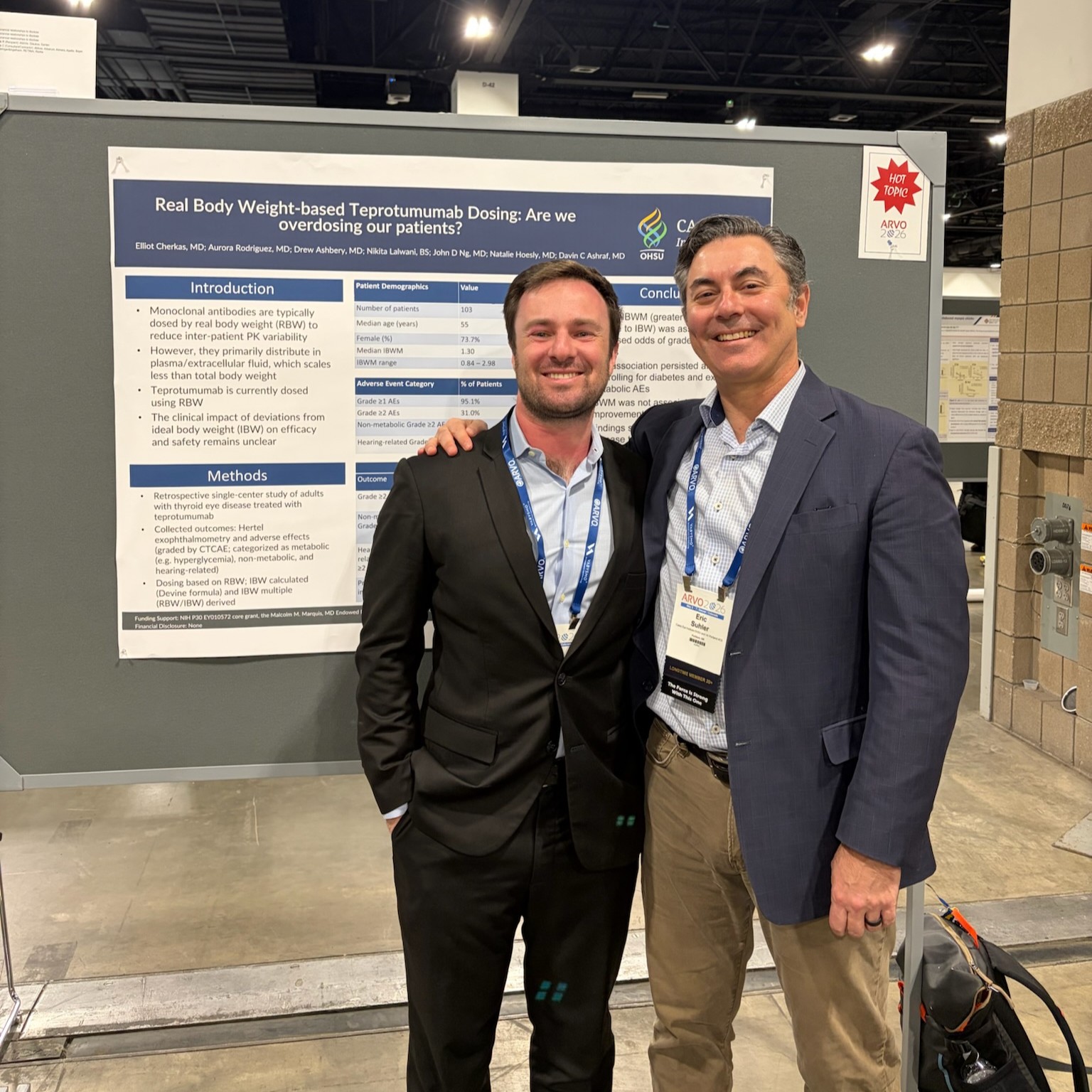 Two men stand together posing in front or a research poster displayed on a large board.