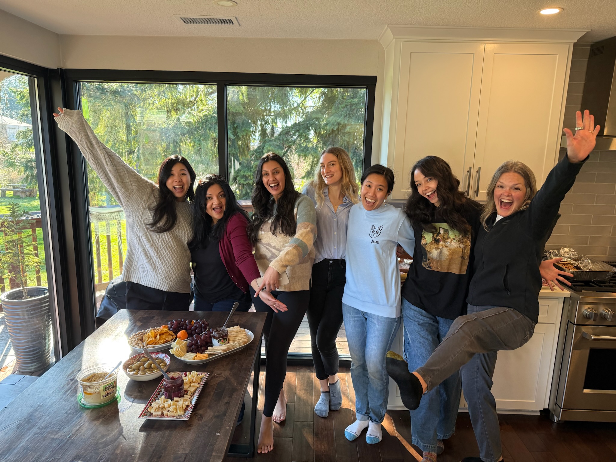 A group of women in casual clothing pose in a row together.