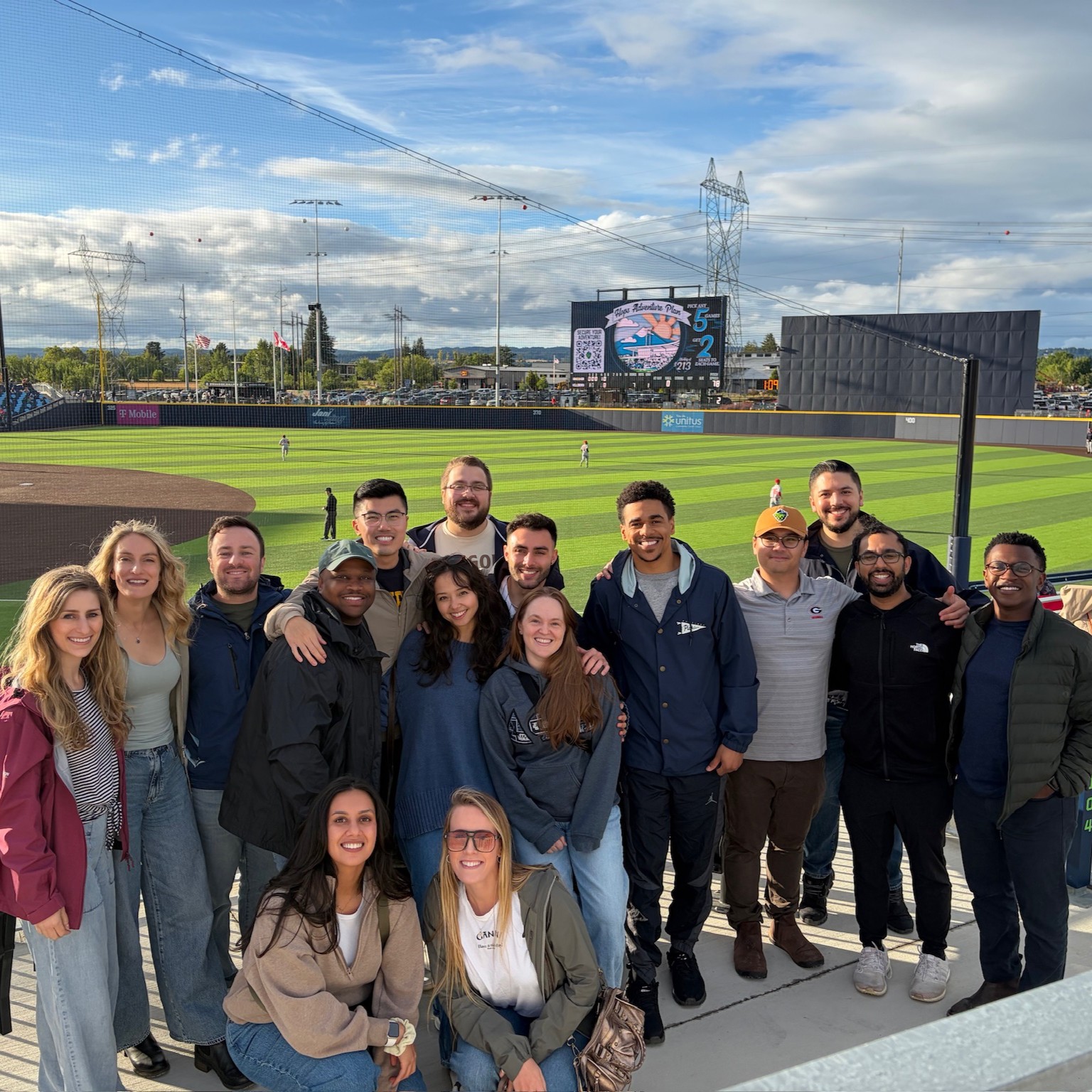 A large group of people pose in front of a professional baseball field.