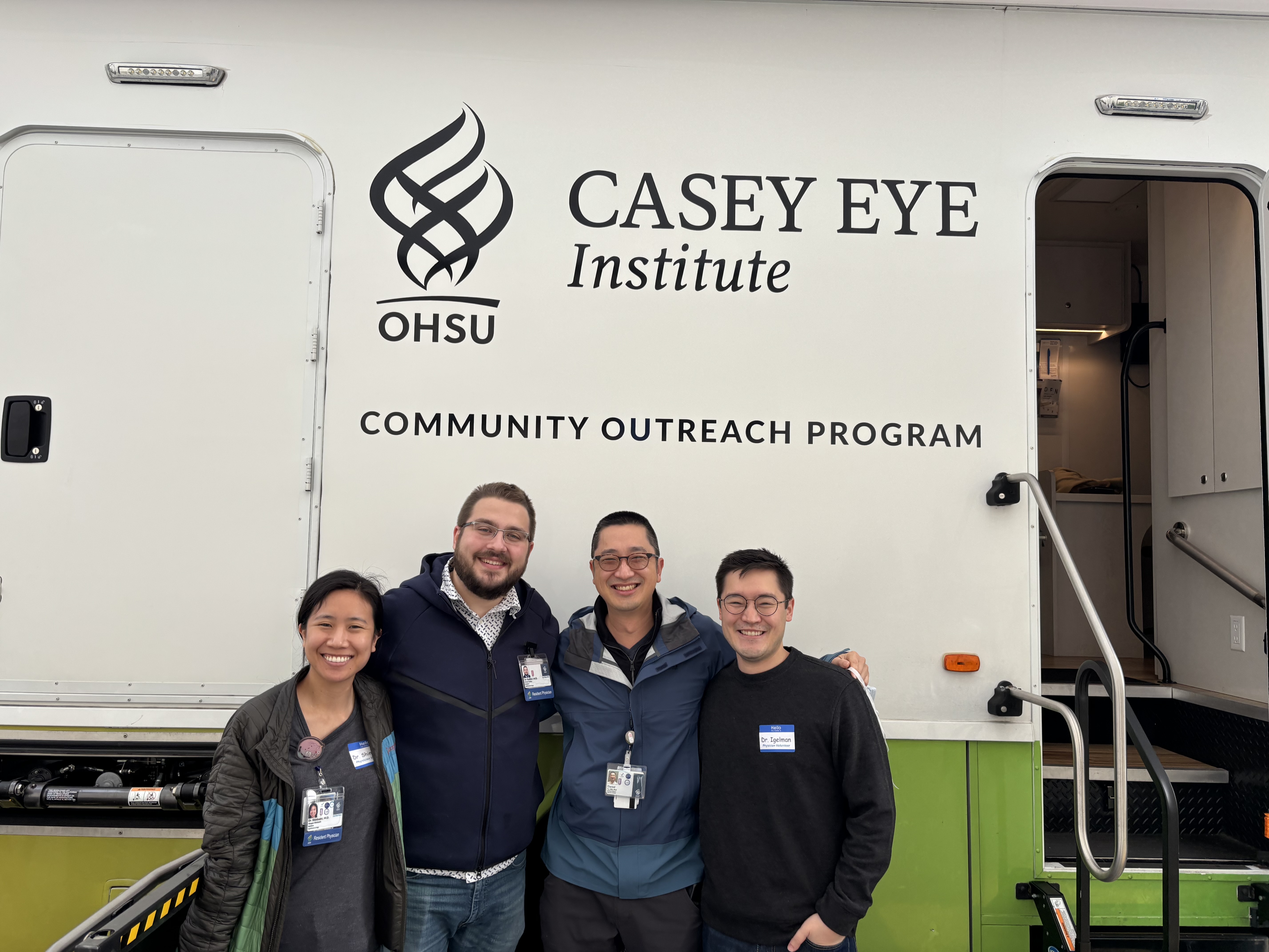 Four people stand together posing for the camera in front of the Casey Outreach Program's mobile clinic.