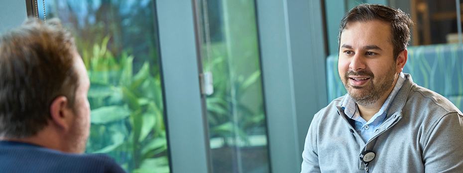 An OHSU doctor sits at a window table talking with another person.