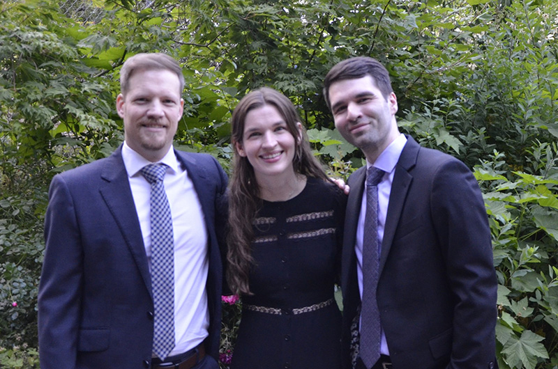 Two men and one woman wearing professional attire and smiling