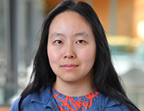 Dr Helen Yang is facing the camera in front of a blurry background.