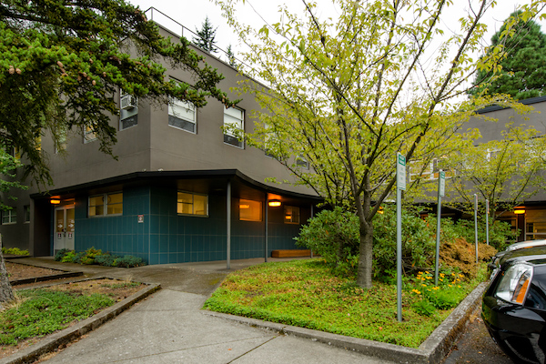 Green building with cement upper with tree in front of it